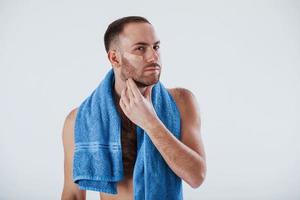 Nice clean skin. Man with blue towel stands against white background in the studio