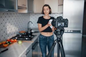 mujer joven atractiva en el marco. chica en la cocina moderna en casa a la hora del fin de semana por la mañana foto