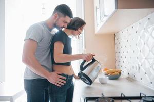 vista desde el lado. pareja joven en la cocina moderna en casa en su tiempo de fin de semana en la mañana foto