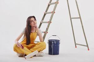 I know what color will be nice for that part of the room. Beautiful brunette in yellow uniform and blue colored bucket sits near the ladder photo