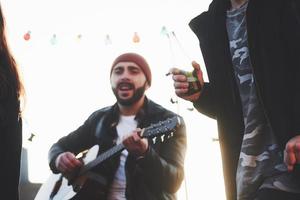 Focused photo. Friends have fun at rooftop party with decorative colored light bulbs photo