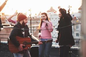 Acting like a rock star. Rooftop party together at warm autumn day photo