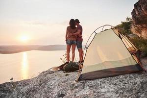 Photo of happy near tent with a view of lake during hiking trip. Travel Lifestyle adventure vacations concept