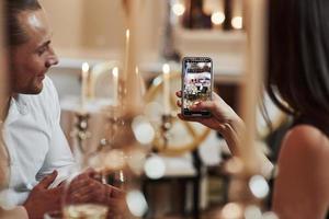 Girl takes photo of pianist. Beautiful couple have romantic dinner in luxury restaurant at evening time