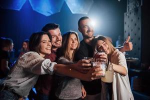 Cheerful mood. Group of young friends smiling and making a toast in the nightclub photo