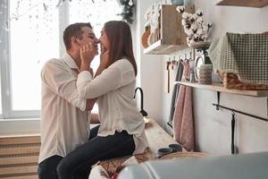 Playing with flour like kids again. Happy couple kissing in the kitchen. Having nice weekend together photo