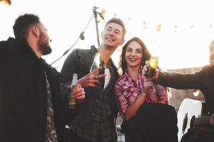 Be ready for the picture. Group of young cheerful friends having fun while takes selfie on the roof with decorate light bulbs photo