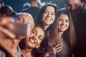 Photo for the memories. Friends taking selfie in beautiful nightclub. With drinks in the hands