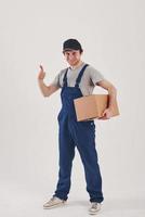 Showing thumb up. Guy with box in hands stands against white background in the studio photo