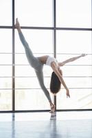 foto vertical. vista lateral de una chica con ropa deportiva haciendo ejercicios de estiramiento en el gran gimnasio espacioso