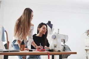 Our dress will be perfect. Two female fashion designers works on the new clothes in the workshop photo