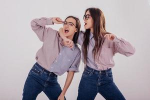 Always together. Two sisters twins standing and posing in the studio with white background photo