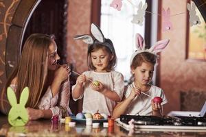 madre orgullosa que tengas felices pascuas. dos niñas aprendiendo a pintar huevos para las fiestas foto