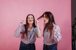 imagina que nací siendo un hombre con un bigote así de grande. dos hermanas gemelas de pie y posando en el estudio con fondo blanco foto