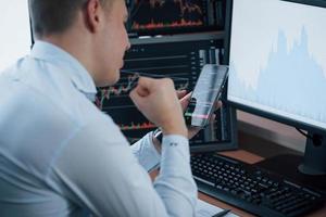 Everything goes awesome. Man working online in the office with multiple computer screens in index charts photo