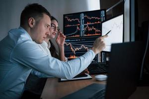 Pay attention to this point of time. Team of stockbrokers are having a conversation in a office with multiple display screens photo