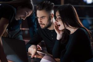 Some shocking content. Team of young business people works on their project at night time in the office photo