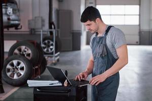 Tires lying on the special stands. Worker stands indoors in uniform does reports, calculations and looking at the plans photo