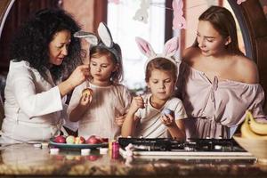 ocio familiar. que tengas felices pascuas. dos niñas aprendiendo de sus padres cómo pintar huevos en las vacaciones foto