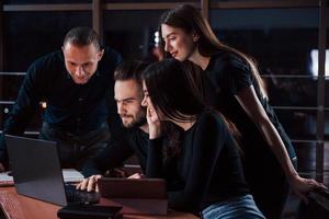 Modern business. Team of young people works on their project at night time in the office photo