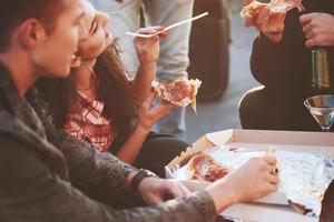 vista de cerca comiendo pizza en la fiesta de la azotea. buenos amigos tienen fin de semana con deliciosa comida y alcohol foto