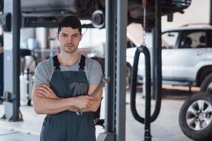 One person in the room. Portrait of serious worker in uniform that stands in his workshop with wrench in hand photo