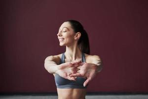 Stretch for the hands. Girl with good fitness body type have exercises in the spacey room photo