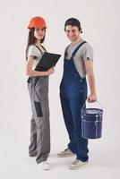 Two employees. Man in blue uniform with woman in hard hat stands against white background in the studio photo
