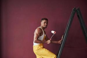 joven trabajador afroamericano en el uniforme amarillo tiene algún trabajo foto