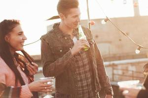 Just relaxing. It's rooftop party. Group of friends have holidays at sunny autumn day photo