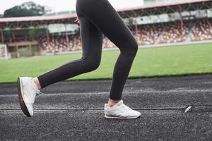 imagen de las piernas solamente. niña corriendo en la pista en el estadio durante el día foto