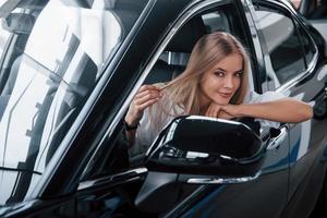 Am I look good today. Beautiful blonde girl sitting in the new car with modern black interior photo