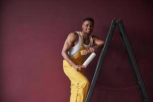 hombre feliz. joven trabajador afroamericano en el uniforme amarillo tiene algún trabajo foto