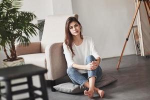 Cozy atmosphere. Young brunette in the room with white walls and daylight that comes from the window photo