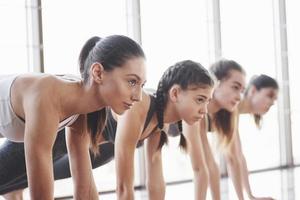 Side view. Group of sportive girls in a spacious gym with big windows have training photo