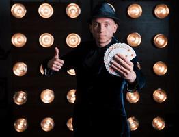 Magician in black suit standing in the room with special lighting at backstage photo