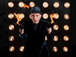Flames from the hands. Professional illusionist in black hat, shirt and gloves playing with fire photo
