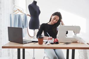 Front view. Female fashion designer works on the new clothes in the workshop photo