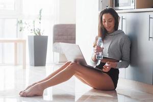 Enjoying fresh water. Girl in the modern kitchen at home at her weekend time in the morning photo