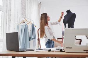 Measures the height of the dummy. Female fashion designer works on the new clothes in the workshop photo