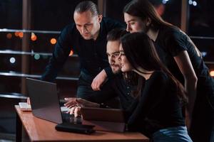 I definitely like the results. Team of young business people works on their project at night time in the office photo