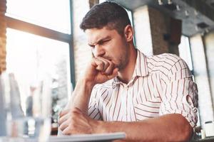 Looks like something wrong. Adult man sits in cafe at daytime and read some hard explained information photo