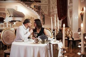 escena clásica con muchas velas y amantes. una pareja hermosa tiene una cena romántica en un restaurante de lujo por la noche foto