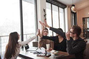 Giving high five gesture. Having fun in the office room. Friendly coworkers playing around and celebrating success photo