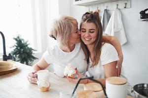 Cute kiss. Mother and daughter having good time in the kitchen photo