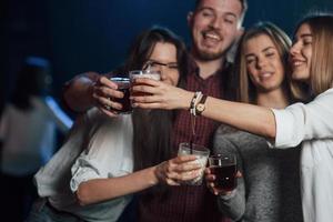 That's is what they call a party. Group of young friends smiling and making a toast in the nightclub photo