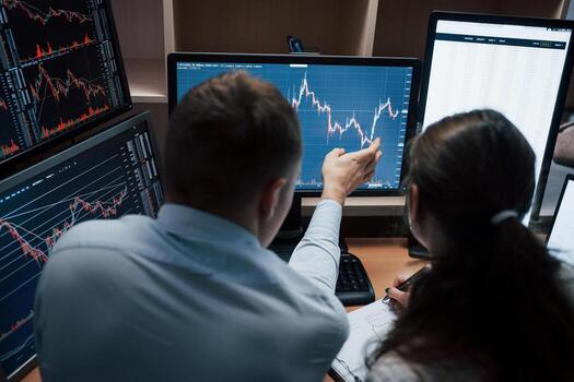 View from the back. Team of stockbrokers are having a conversation in a office with multiple display screens photo