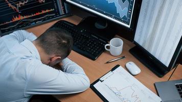 In stress because unexpected fail. Man working online in the office with multiple computer screens in index charts photo
