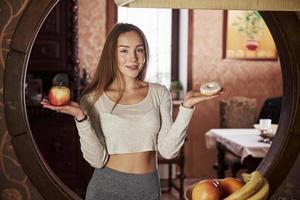 concepción de la alimentación natural saludable. bastante joven de pie en la cocina moderna cerca de la estufa de gas foto