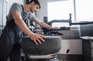 Healthy strong guy. Young man works with wheel's disks at the workshop at daytime photo